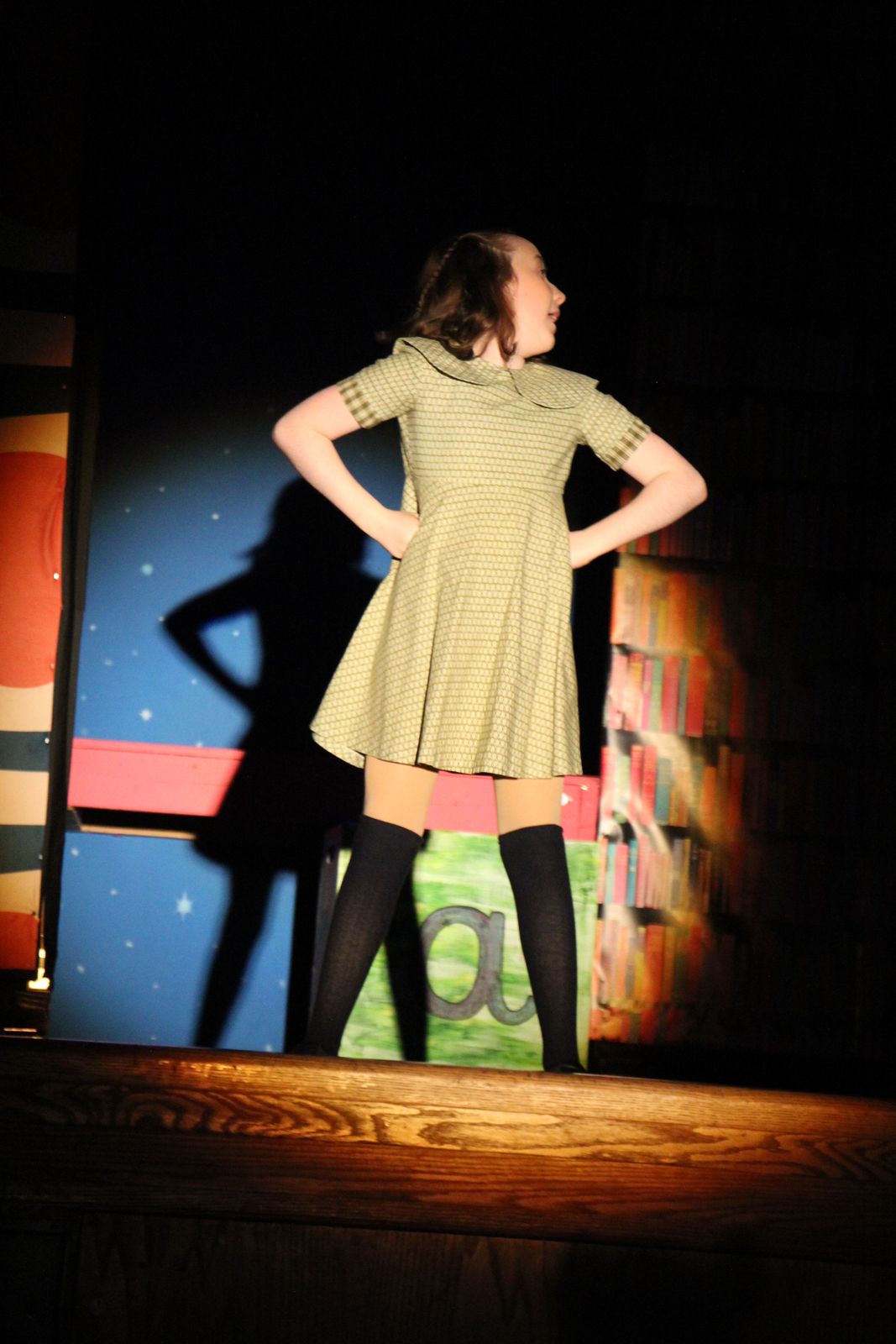 A young performer as Matilda, alone in a spotlight